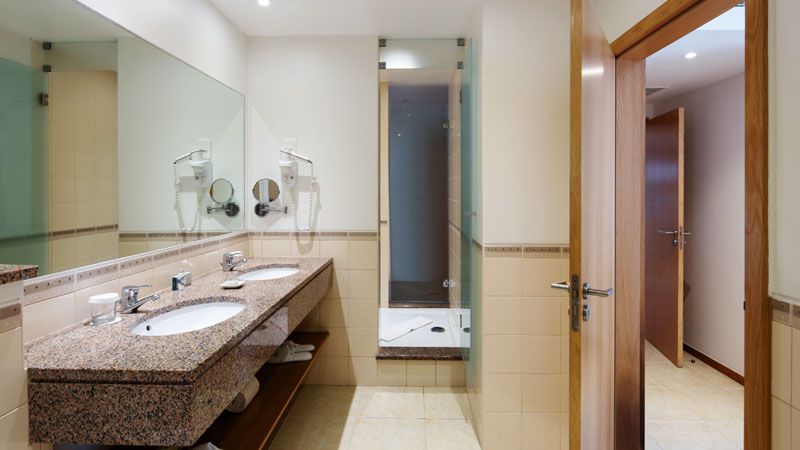 Vale de Oliveiras badrum i lägenhet med två sovrum, där två badrum delar en dusch